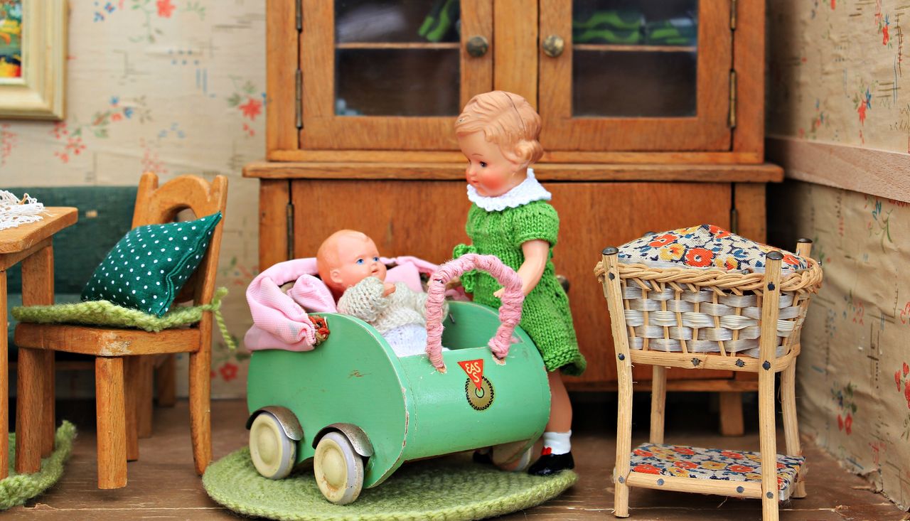 Intricate dollhouse scene featuring antique toys and furniture depicting childhood play.